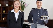 Happy concierge and receptionist in hotel waiting at counter Happy concierge and receptionist in hotel waiting at counter